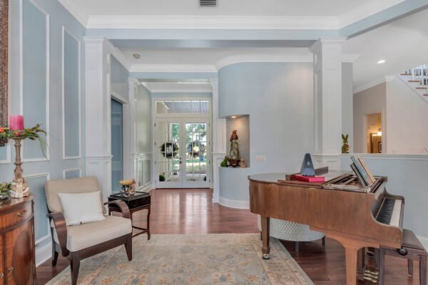 Elegant entryway of a custom-built estate at 6264 Blakeford Drive, featuring a grand piano, stylish armchair, and decorative elements, showcasing the luxurious interior design relevant to Windermere real estate market.