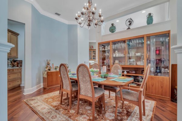 Elegant dining room featuring a wooden table set for six, surrounded by upholstered chairs, a chandelier above, and a glass-fronted cabinet displaying fine china, all within a well-lit space that highlights the home's sophisticated design.