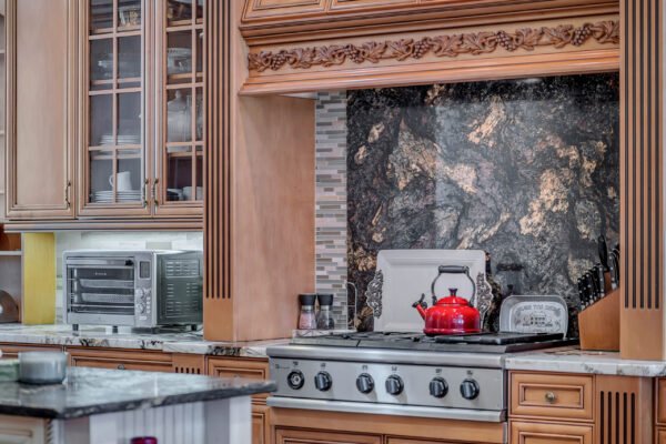 Custom kitchen with high-end appliances, granite countertops, and a red kettle on the stove, showcasing luxury design elements in a Windermere estate.