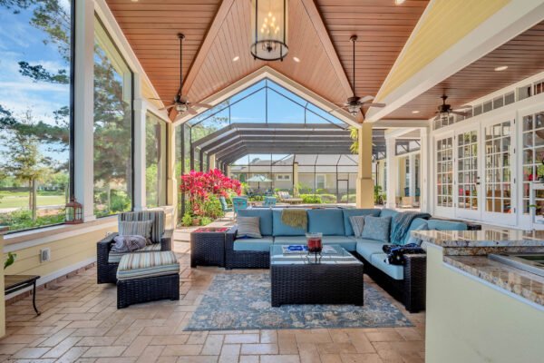 Luxurious sunroom with comfortable seating, large windows showcasing landscaped backyard and golf course views, featuring vibrant flowers and elegant decor, ideal for entertaining in the custom-built estate at 6264 Blakeford Drive, Windermere, FL.