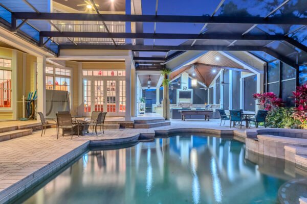 Luxury backyard with pool and spa, covered lanai, outdoor kitchen, and seating area, showcasing the custom-built estate at 6264 Blakeford Drive in Windermere, Florida.