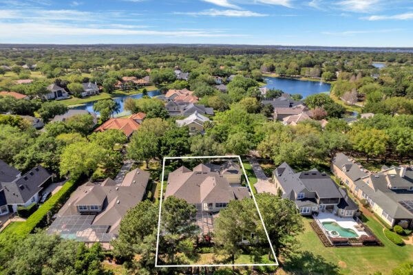 Aerial view of 6264 Blakeford Drive, Windermere, FL, showcasing a custom-built estate with landscaped grounds, adjacent to the Golden Bear Championship Golf Course, featuring nearby homes and a pool in the backyard.
