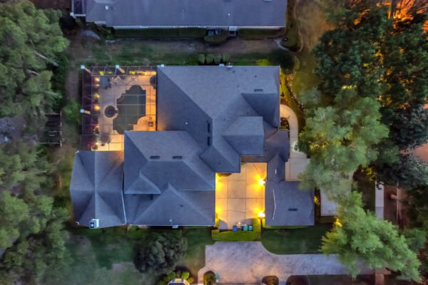 Aerial view of a custom-built estate at 6264 Blakeford Drive in Windermere, showcasing a spacious layout with illuminated outdoor areas, pool, and landscaped grounds adjacent to the Golden Bear Championship Golf Course.