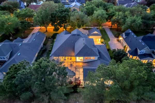 Aerial view of a custom-built estate at 6264 Blakeford Drive, Windermere, FL, showcasing a spacious backyard with a pool, surrounded by mature trees and neighboring homes, emphasizing the property's luxurious design and landscaping.