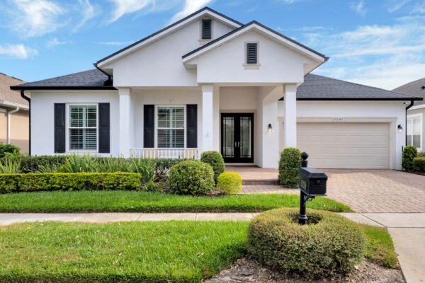 Single-story home in Windermere, Florida, featuring a modern facade, manicured landscaping, and a welcoming front porch, ideal for showcasing real estate listings.