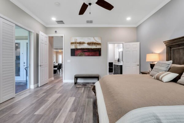 Spacious master bedroom featuring a king-sized bed, modern decor, and access to ensuite bathroom, showcasing elegant design elements and premium flooring.