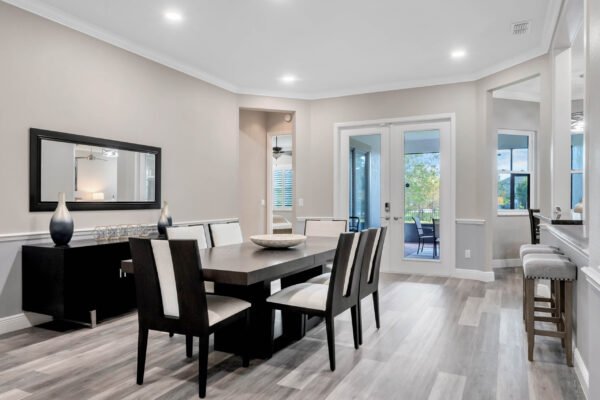 Modern dining area in Windermere home featuring a sleek table with upholstered chairs, contemporary decor, and large windows overlooking a patio.