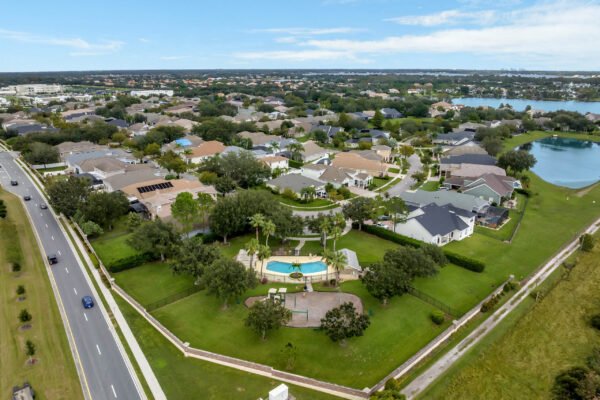 Aerial view of residential neighborhood in Windermere, Florida, featuring homes, manicured lawns, and a community pool surrounded by greenery, highlighting the charm of the area near 13230 Fossick Road.