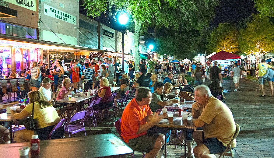 Crowd enjoying food and festivities at Winter Garden MusicFest, with lively street performances and illuminated storefronts in downtown Winter Garden.
