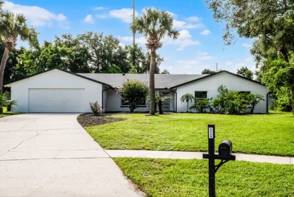 Single-story residential home at 8908 Turnberry Ct, Orlando, FL, featuring a manicured lawn, palm trees, and a driveway leading to a garage.